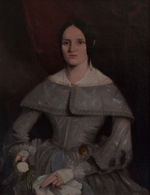 Portrait of seated dark-haired woman with white-collared and cuffed, grey ornate dress holding a flower in her right hand.