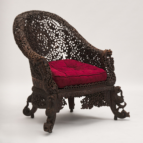 Elaborately carved and pierced chair. Scroll feet with lion and bird. Maroon damask upholstered cushion.