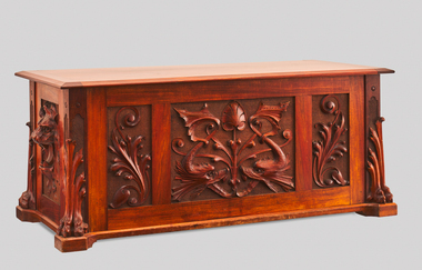 Wooden blanket box featuring ornate carving in the lower half featuring fish, lions and decorative scroll work.