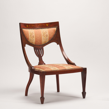 Carved wooden chair with a padded seat and back rest. Fabric is striped in cream and faded red with a floral scroll motif.