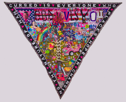 A triangular textile hangs with the tip pointed towards the floor. Around the rim the words "Cursed is everyone who places hope in changing the nature of man" in the centre is a colourful and busy collection of multi-layered mixed media items.