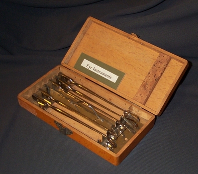 WOODEN CASE WITH METAL CLASP AND 6 STAINLESS STEEL OPTHALMIC INSTRUMENTS