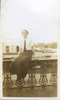 Black and white photograph of a young lady sitting on the balcony of the Club Hotel, Fraser Street, Clunes