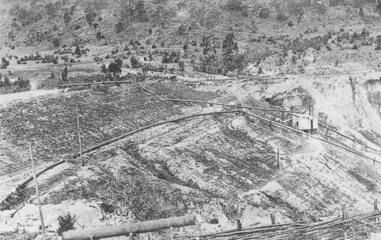 Aerial photograph of mining site with long sluicing pipes and small processing shed.