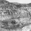 Open cut mine with pipes protruding from processing shed.