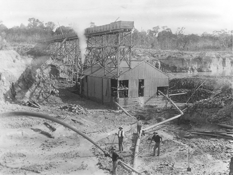 Open cut hydraulic mining with barge, water pipes and sluice boxes.