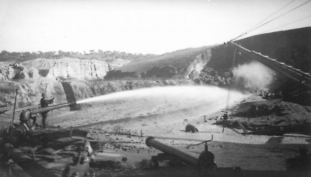 Man operating hydraulic jet canon at open cut mine.