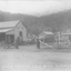 Three wooden buildings, horse and cart.