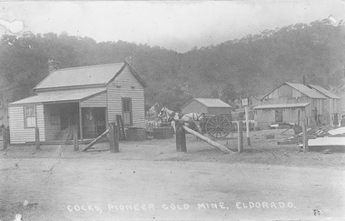 Three wooden buildings, horse and cart.