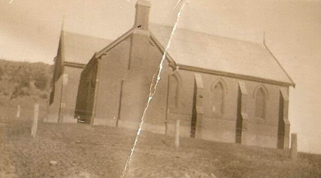 Brick building with arched windows, chimney and vestibule.