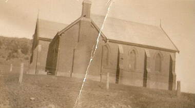 Brick building with arched windows, chimney and vestibule.