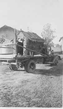 Flat bed truck carrying a small hut.