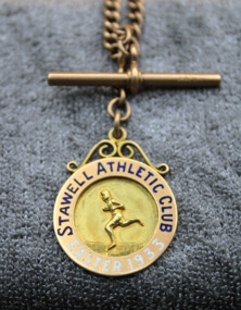 Gold medal with on rose gold chain. Raised running figure, inscriptions on bezel