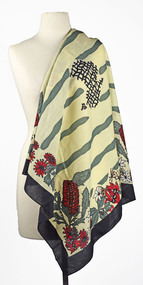 shawl with green, red, black and cream print draped over shoulder of mannequin 
