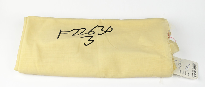folded cream fabric with paper tag and number written in black ink on fabric