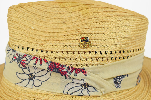detail of straw hat and floral textile band and pin