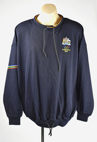 front view of navy jumper with small band of coloured stripes around one arm, a logo over chest and toggles around neck and waist