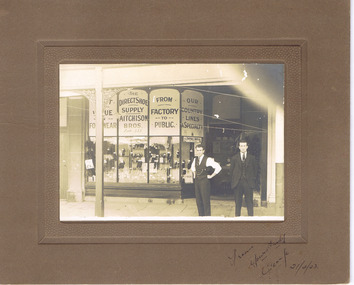 Two men standing in front of Aitchison Bros shoe shop. 