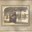 View from street of front of Miller Brothers China and Glass shop. Two men stand in the doorway.