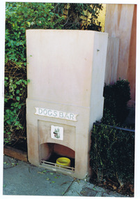 A fireplace with a yellow bowl in the hearth. On the front is a picture of a dog and a sign with the words 'Dogs Bar'. 