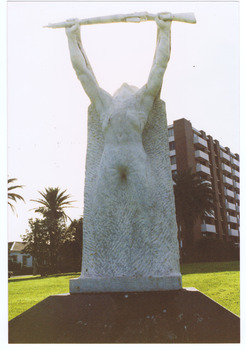 White sculpted figure of a soldier holding a rifle above his head. The statue stands on a red plinth.