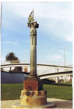 A tall stone ionic column on a square pedestal that has a tap on each side. Under each tap is a granite basin decorated with a bronze scallop shell. At the top of the column is a bronze sculpture of a sailing ship. There are metal decorations on the column.