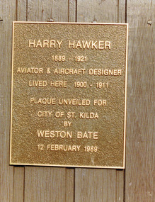 Rectangular metal plate inscribed with the following words: Harry Hawker 1889-1921 Aviator & Aircraft Designer lived here 1900-1911. Plaque unveiled for City of St Kilda by Weston Bate 12 February 1989