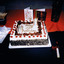 A square cake decorated with candles, icing and the words Happy 35th Birthday. Next to the cake are plates, table napkins, cutlery, two cards and a wrapped gift.