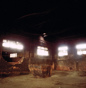 Brick walls, windows and metal skip inside a building.