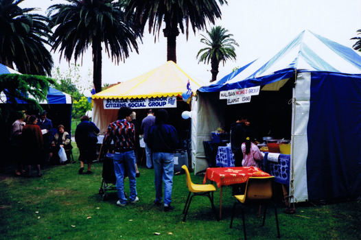 People visiting three gazebos in a park