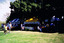 People visiting a row of gazebos in a park.