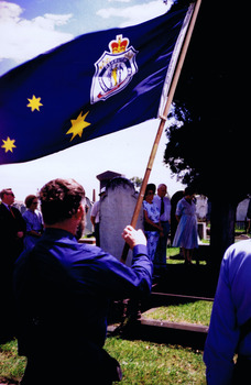 Man holding RSL flag, seen from behind
