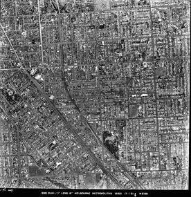 Rooftops, roads, trees and open spaces seen from the air directly above.