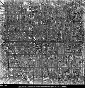 Rooftops, roads, trees and open spaces seen from the air directly above.
