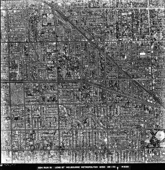 Rooftops, roads, trees and open spaces seen from the air directly above.