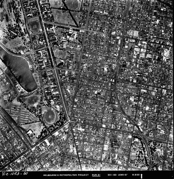 Rooftops, roads, trees and open spaces seen from the air directly above.