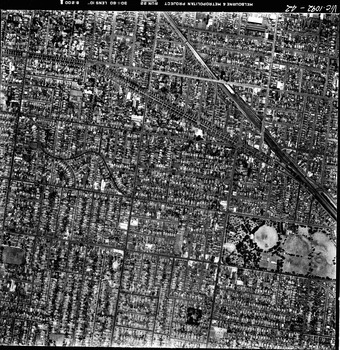 Rooftops, roads, trees and open spaces seen from the air directly above.