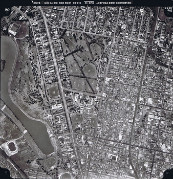 Rooftops, roads, trees and open spaces seen from the air directly above.
