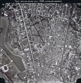 Rooftops, roads, trees and open spaces seen from the air directly above.