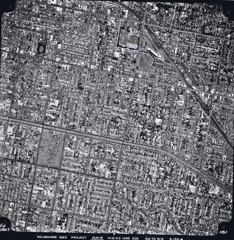 Rooftops, roads, trees and open spaces seen from the air directly above.