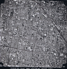 Rooftops, roads, trees and open spaces seen from the air directly above.