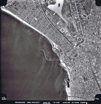 Rooftops, roads, trees, open spaces and shoreline seen from the air directly above.