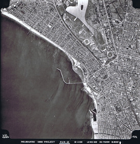 Rooftops, roads, trees, open spaces and shoreline seen from the air directly above.