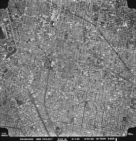 Rooftops, roads, trees and open spaces seen from the air directly above.