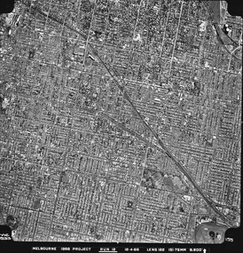 Rooftops, roads, trees and open spaces seen from the air directly above.