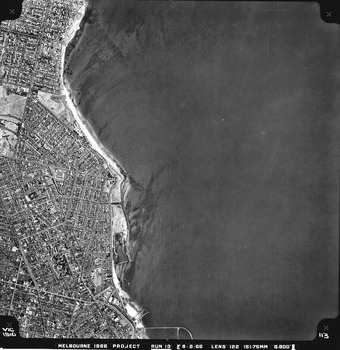 Rooftops, roads, trees, open spaces and shoreline seen from the air directly above.