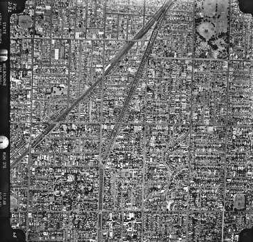 Rooftops, roads, trees and open spaces seen from the air directly above.