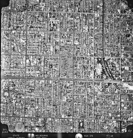 Rooftops, roads, trees and open spaces seen from the air directly above.
