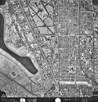 Rooftops, roads, trees and open spaces seen from the air directly above.