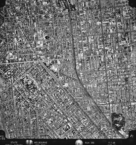 Rooftops, roads, trees and open spaces seen from the air directly above.